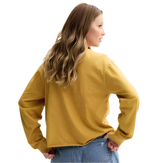 Woman wearing a mustard yellow long-sleeve top on a light gray background