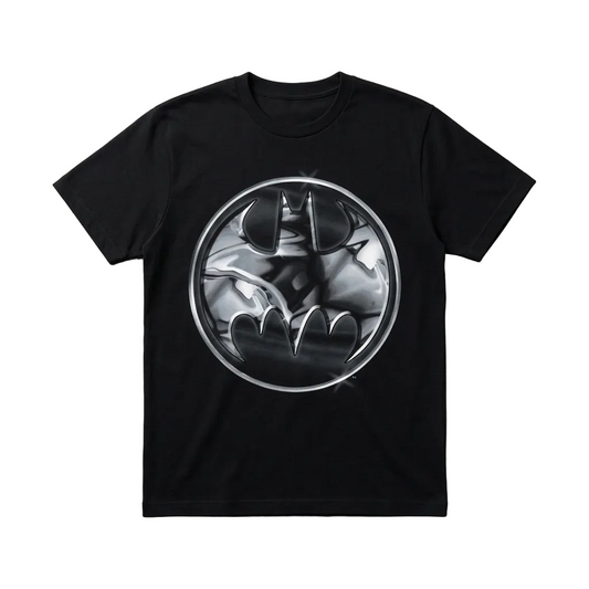 A black short-sleeve crewneck t-shirt featuring a circular metallic silver and black Batman graphic printed on the chest, displayed flat against a textured gray background.