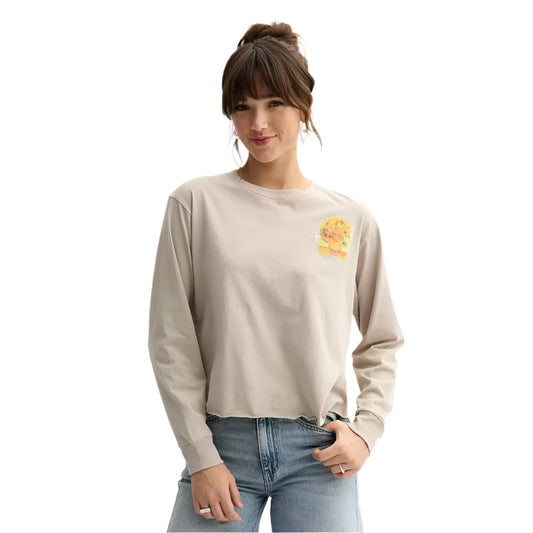 Woman wearing a beige long-sleeve shirt with a small graphic on a plain background