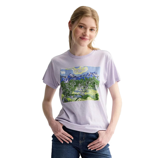 A woman modeling a light purple crewneck t-shirt with a colorful Van Gogh style landscape graphic on the front, paired with dark blue jeans, against a plain light gray background.