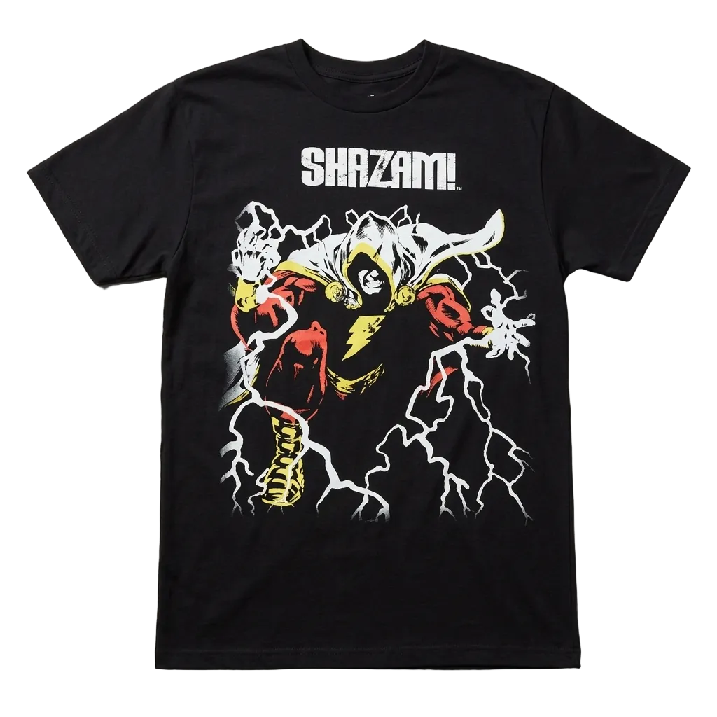 A black short-sleeve graphic t-shirt featuring a stylized illustration of Shazam! in a red and yellow costume with white lightning effects, and the word 'SHAZAM!' printed in white above the graphic, laid flat on a light gray textured background.