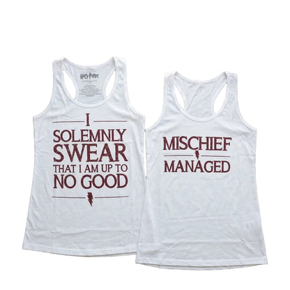 Two white tank tops with text on a wooden surface.