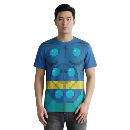 A man wearing a blue short-sleeve t-shirt with a pixelated robot face graphic in shades of blue, teal, and yellow, paired with dark gray jeans, standing against a neutral gray studio background.