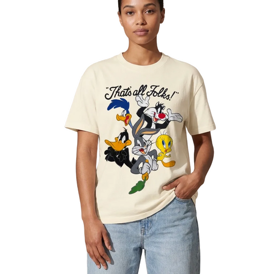 A model wearing a cream-colored graphic t-shirt featuring Looney Tunes characters and the text 'Thats all Folks!' on the front, paired with light-wash blue jeans against a neutral studio background. 