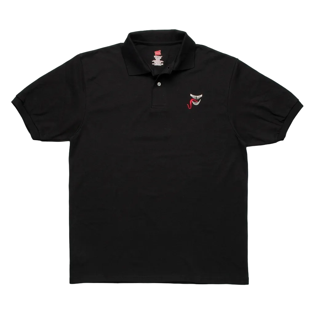 A black short-sleeve polo shirt laid flat on a light gray textured background, featuring a small embroidered red and white shark face logo on the left chest.