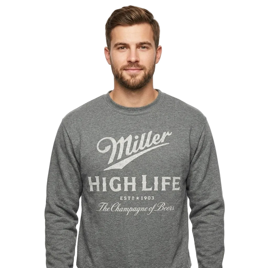 A man wearing a heather gray long-sleeve crewneck sweatshirt with a distressed white graphic print that reads 'Miller High Life' and 'The Champagne of Beer'.