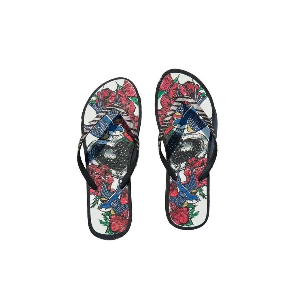 Flip-flops with floral and bird design on a concrete surface near a pool. 