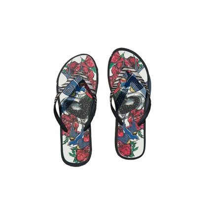 Flip-flops with floral and bird design on a concrete surface near a pool. 