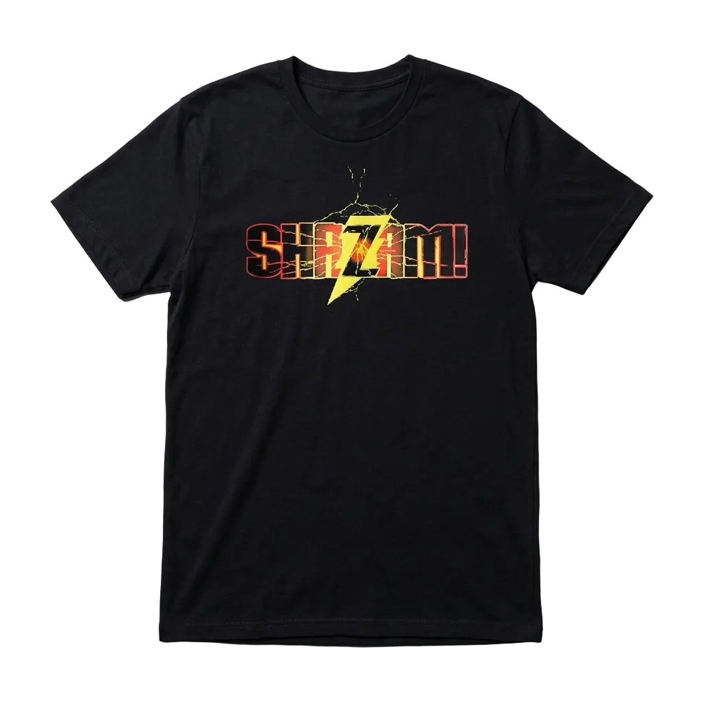 A black short-sleeve crewneck t-shirt featuring a graphic print on the chest with the word 'SHAZAM!' in orange-red outlined letters and a yellow lightning bolt in the center, laid flat on a textured gray background.