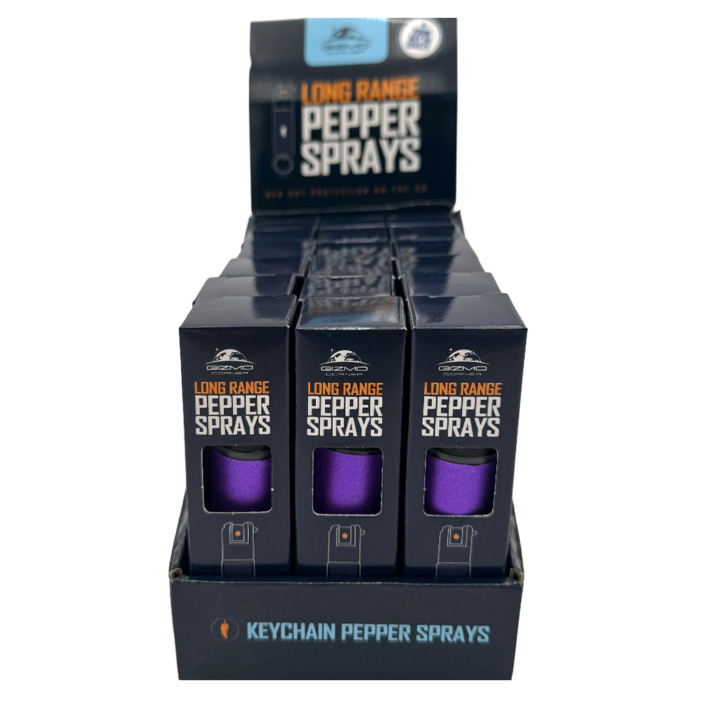 Display of long-range pepper spray keychain sprays in black packaging with purple canisters.