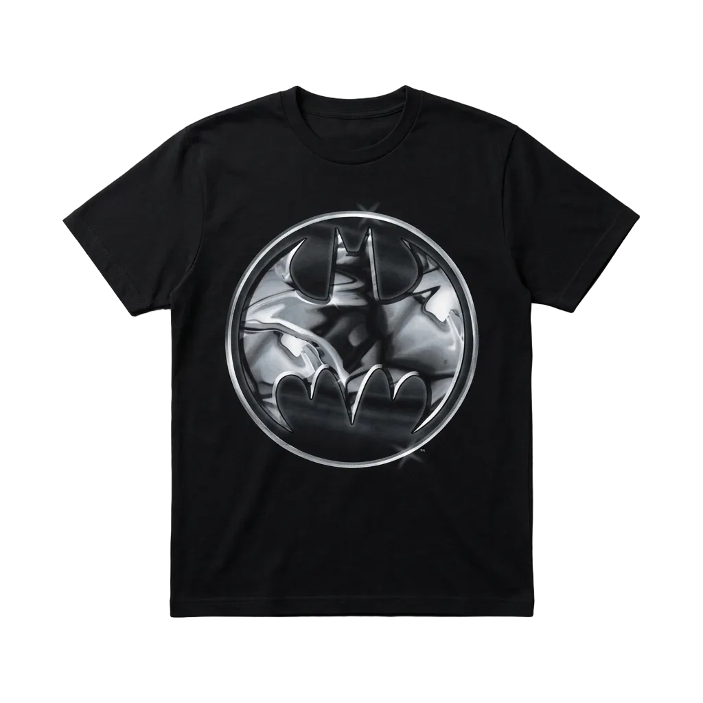 A black short-sleeve crewneck t-shirt featuring a circular metallic silver and black Batman graphic printed on the chest, displayed flat against a textured gray background.