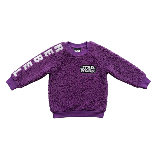 A purple sherpa fleece sweatshirt for kids, featuring 'STAR WARS' printed on the chest and 'EMBA' in white letters across the right sleeve, laid flat on a light gray concrete surface.