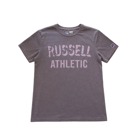 Gray t-shirt with 'Russell Athletic' text on a light gray surface with flowers and a mug. 