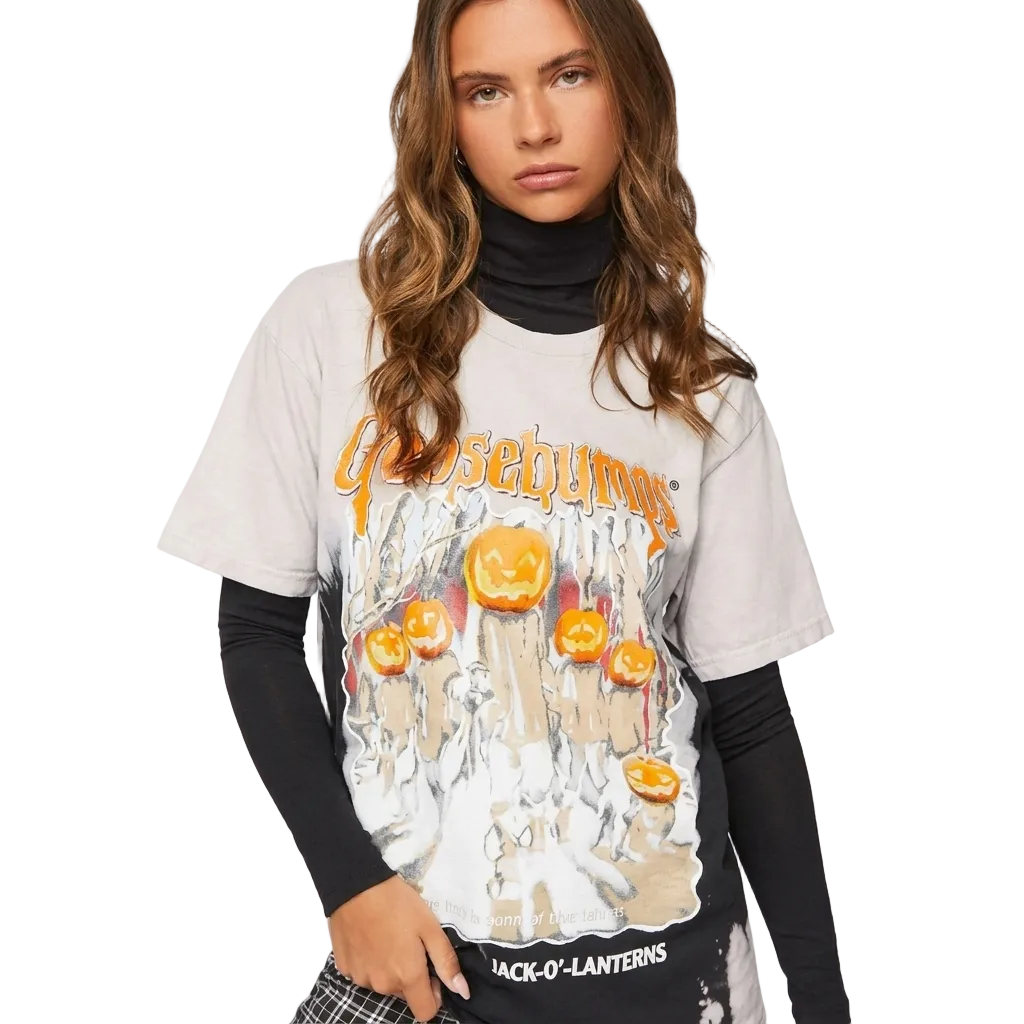 A woman wearing a Goosebone Halloween graphic t-shirt over a black turtleneck and black long-sleeve undershirt, posed against a solid off-white background.
