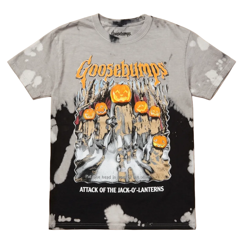 A Goosebumps graphic t-shirt featuring the 'Attack of the Jack-O-Lanterns' design, laid flat on a light wood background. The shirt has a gray and black tie-dye pattern with white splatter details, and features the Goosebumps logo and a graphic of pumpkins and a haunted house.