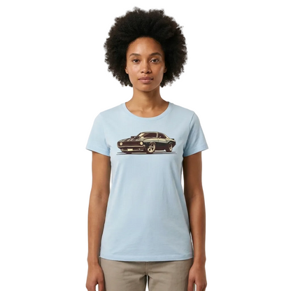 A woman with an afro hairstyle wearing a light blue crewneck t-shirt with a vintage muscle car graphic on the chest, paired with beige pants, set against a plain off-white background.