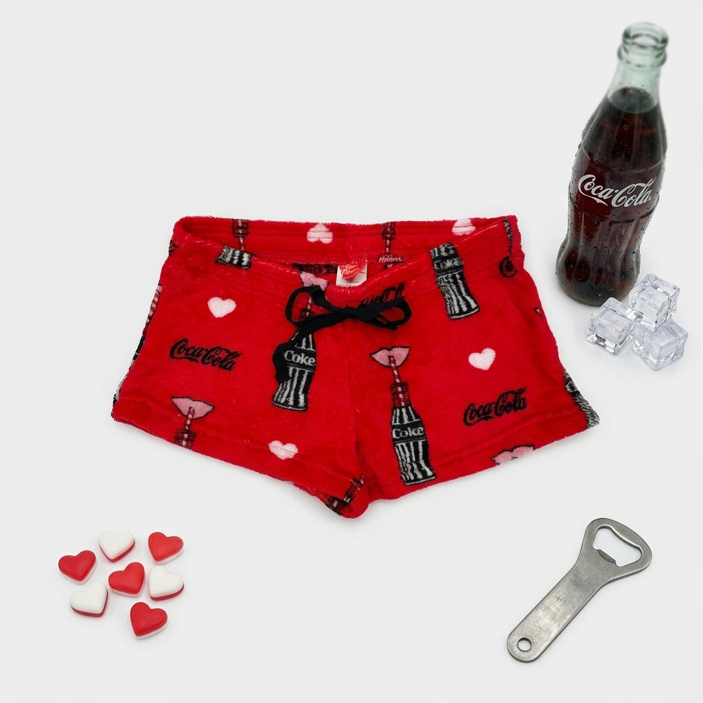 Women's red Coca-Cola Love fleece shorts by Bioworld, featuring a cozy sleepwear design with Coca-Cola branding and heart graphics.