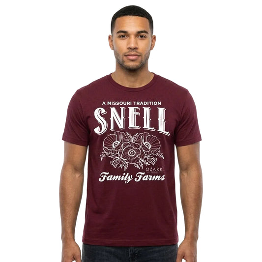 A man wearing a maroon short-sleeve t-shirt with a white graphic print that reads 'A MISSOURI TRADITION SNEELL CARK Family Farms' and features a ram illustration, set against a plain white background.