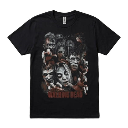 A black short-sleeve graphic t-shirt featuring a collage of zombie faces and the 'The Walking Dead' logo printed in red on the front, laid flat on a textured gray background.