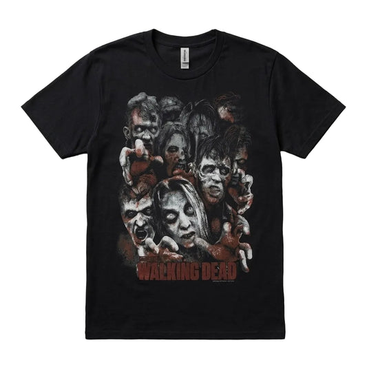 A black short-sleeve graphic t-shirt featuring a collage of zombie faces and the 'The Walking Dead' logo printed in red on the front, laid flat on a textured gray background.